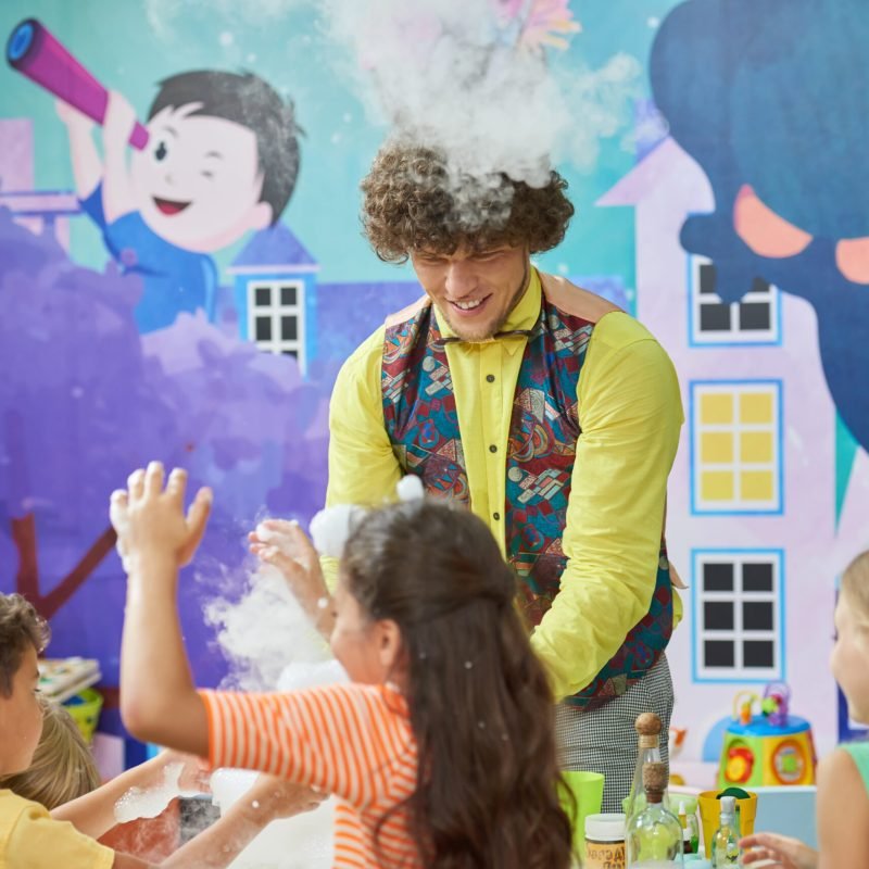 Joyful kids in entertainment center. Joyful kids in entertainment center. Cheerful entertainer doing science show for kids. Childrens entertainment and education.